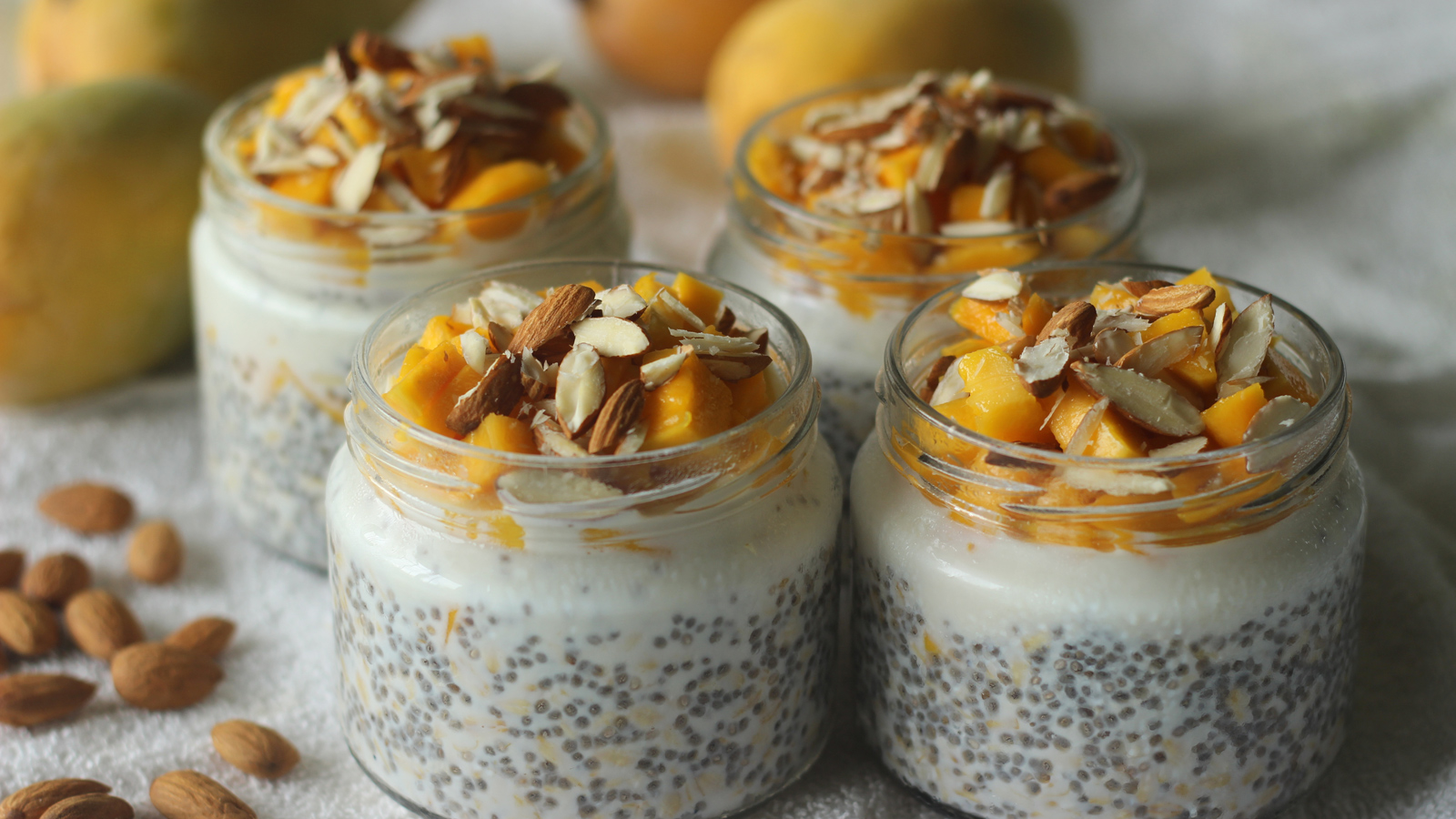 Ideas for healthy breakfast meal prep. Meal prep jars filled with overnight oats and topped with tropical fruit and nuts.