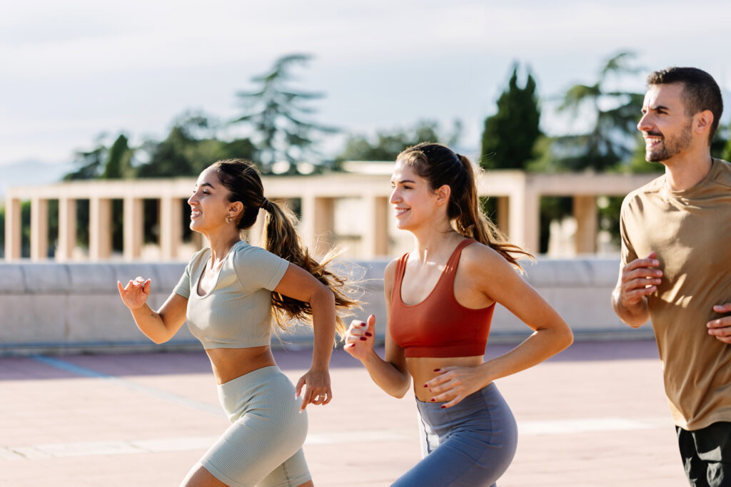 Image of 3 friends running together outdoors.