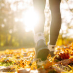 Image of a woman walking through autumn leaves