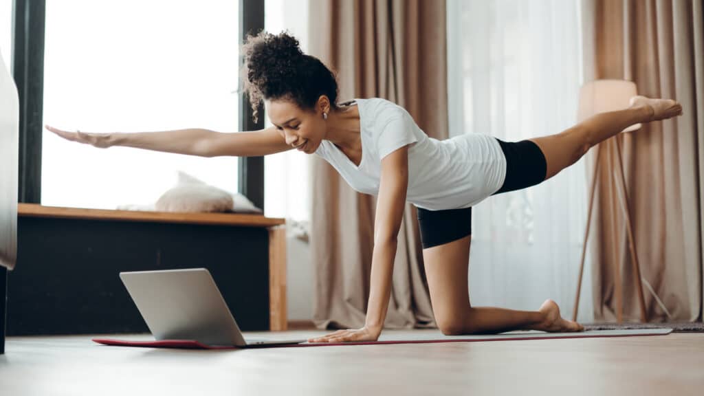 Image of a young woman practicing yoga by watching a yoga video for beginners