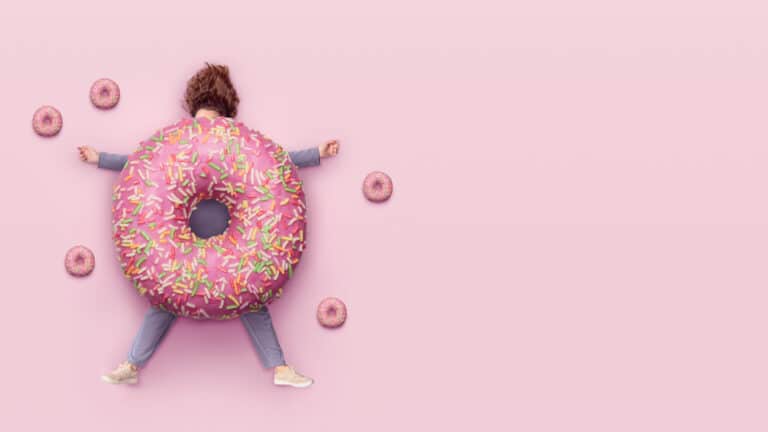 Image of a woman squashed by a donut to illustrate quitting sugar