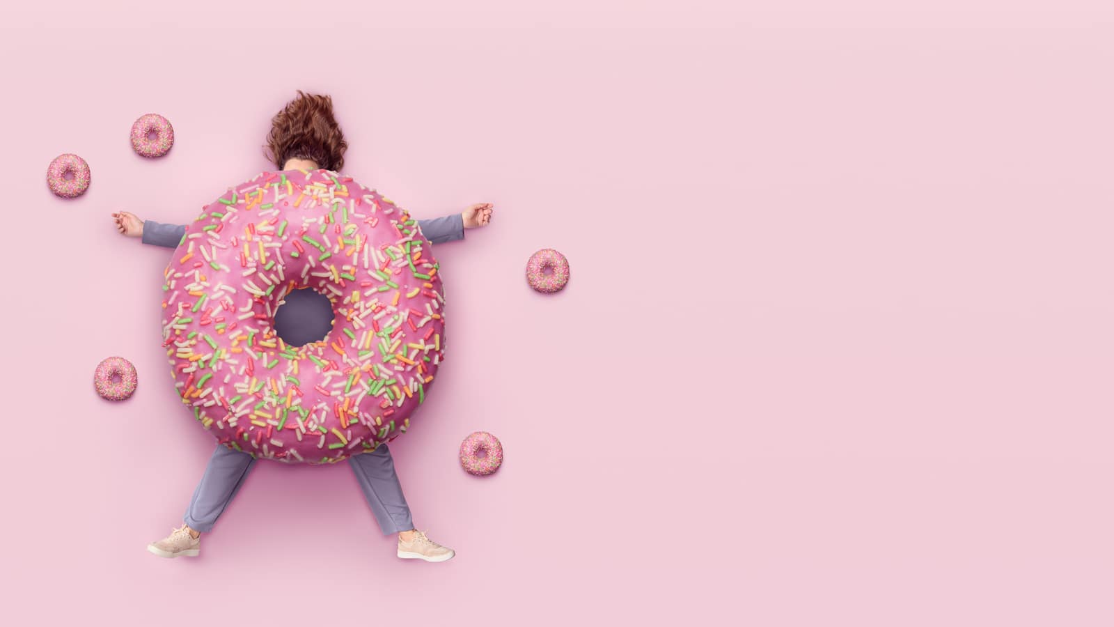 Image of a woman squashed by a donut to illustrate quitting sugar